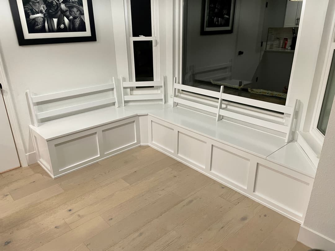 Corner built-in seating area with white paneling in a modern interior.