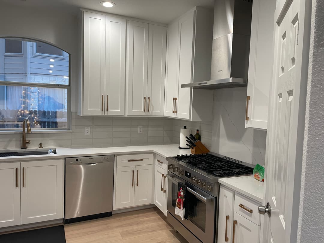 Modern kitchen with white cabinets, stainless steel appliances, and a large gas range.