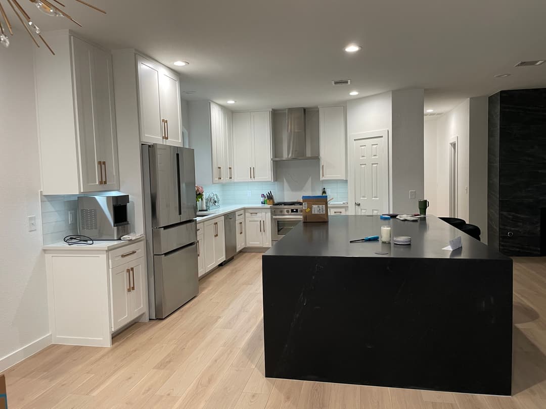 Modern kitchen with white cabinets, stainless steel appliances, and a large black island countertop.