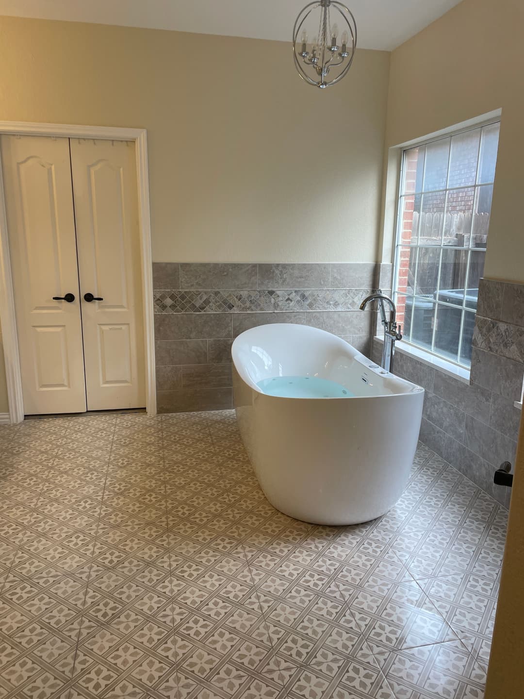 Modern bathroom featuring a freestanding tub, decorative tiles, and natural light.