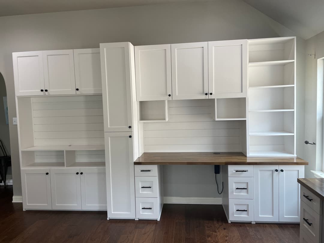 Modern white office furniture with shelving and a wooden desk in a bright room.