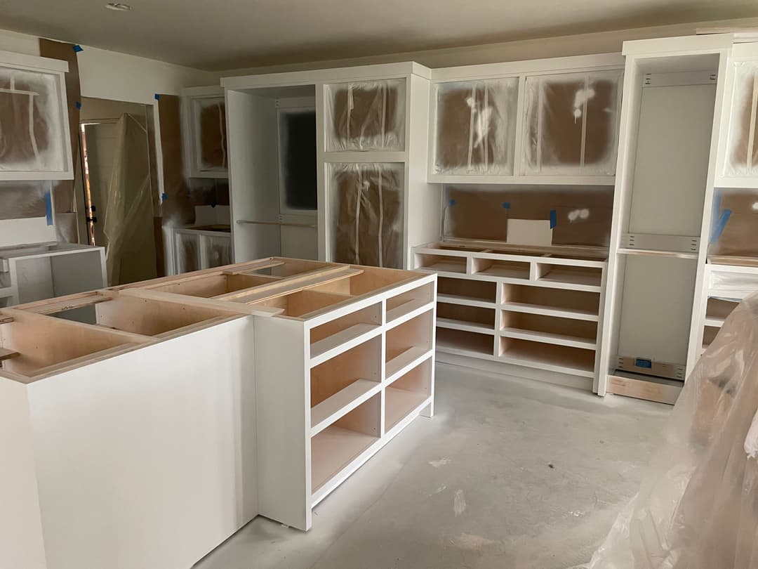 Newly installed kitchen cabinets in a renovated space, covered for protection.