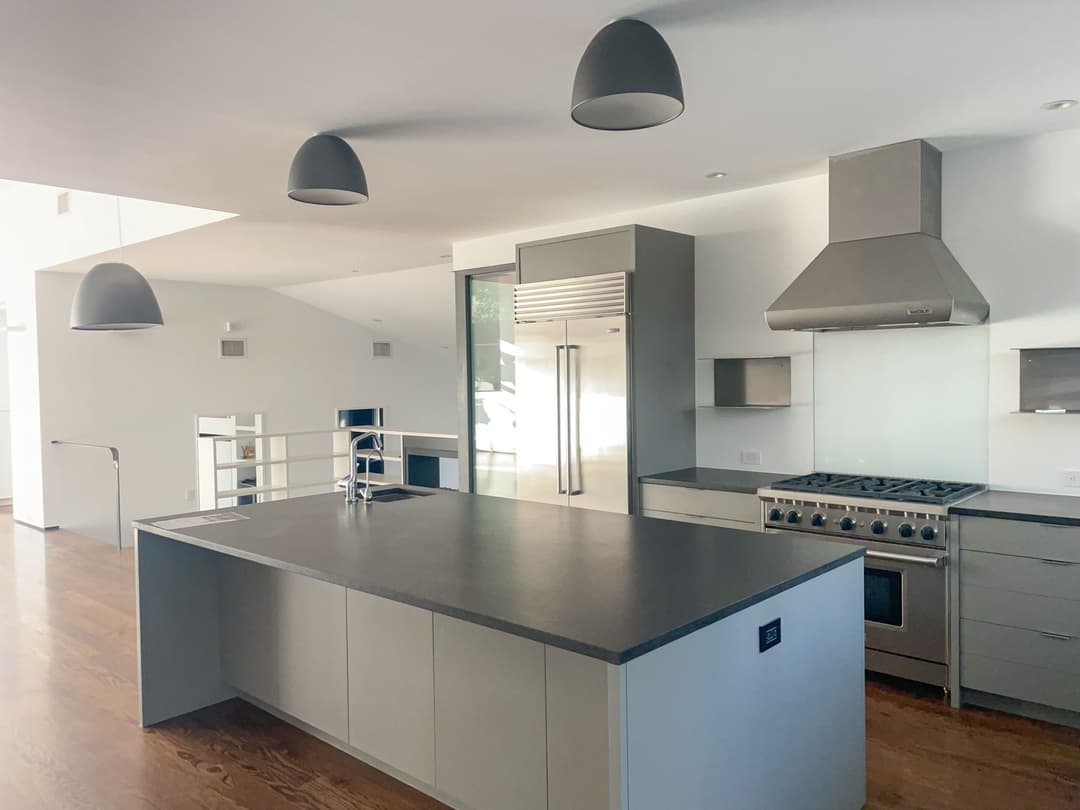 Modern kitchen with sleek gray cabinets, stainless steel appliances, and wooden flooring.