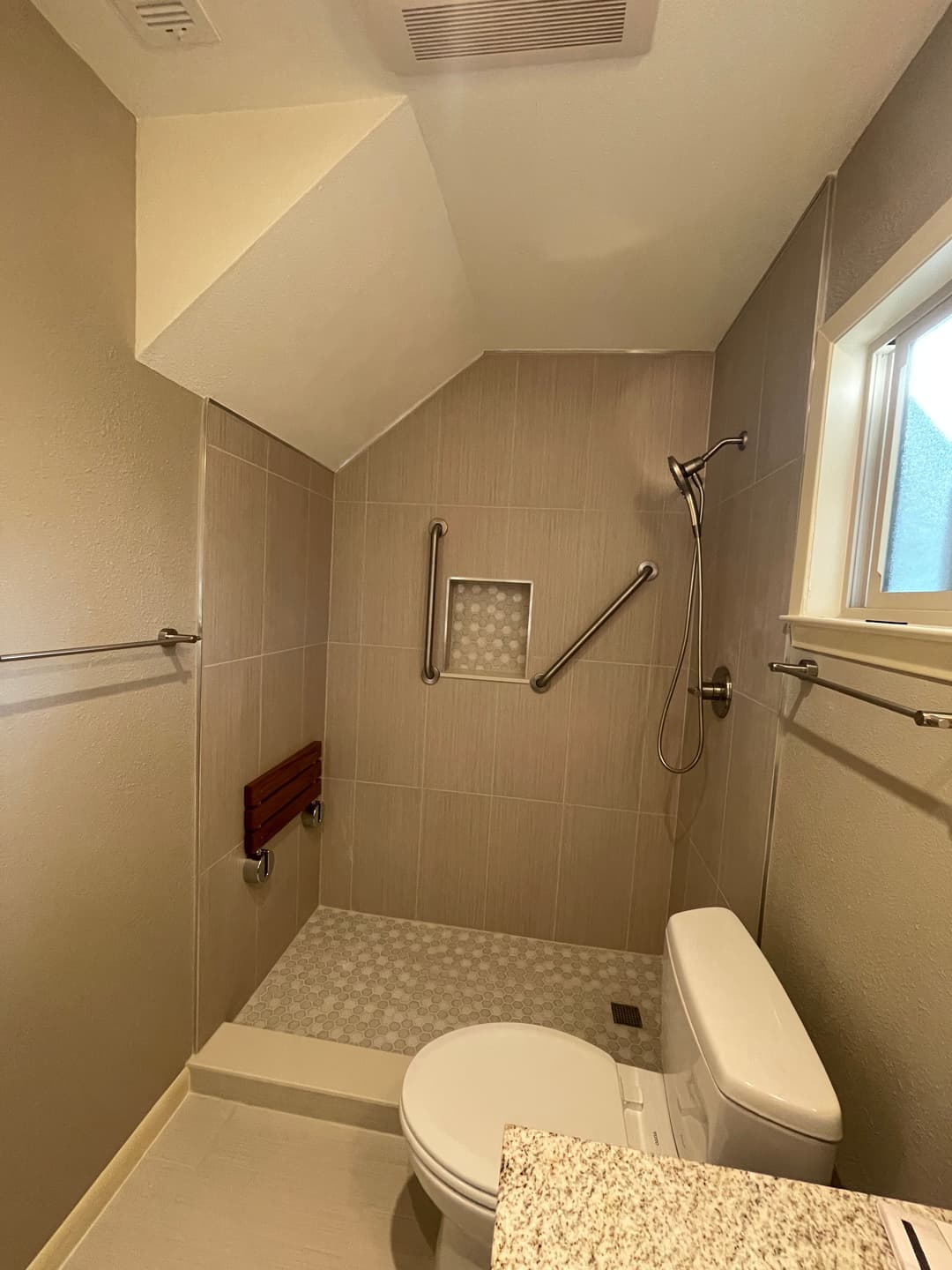 Accessible bathroom with shower, grab bars, toilet, and modern tile design.