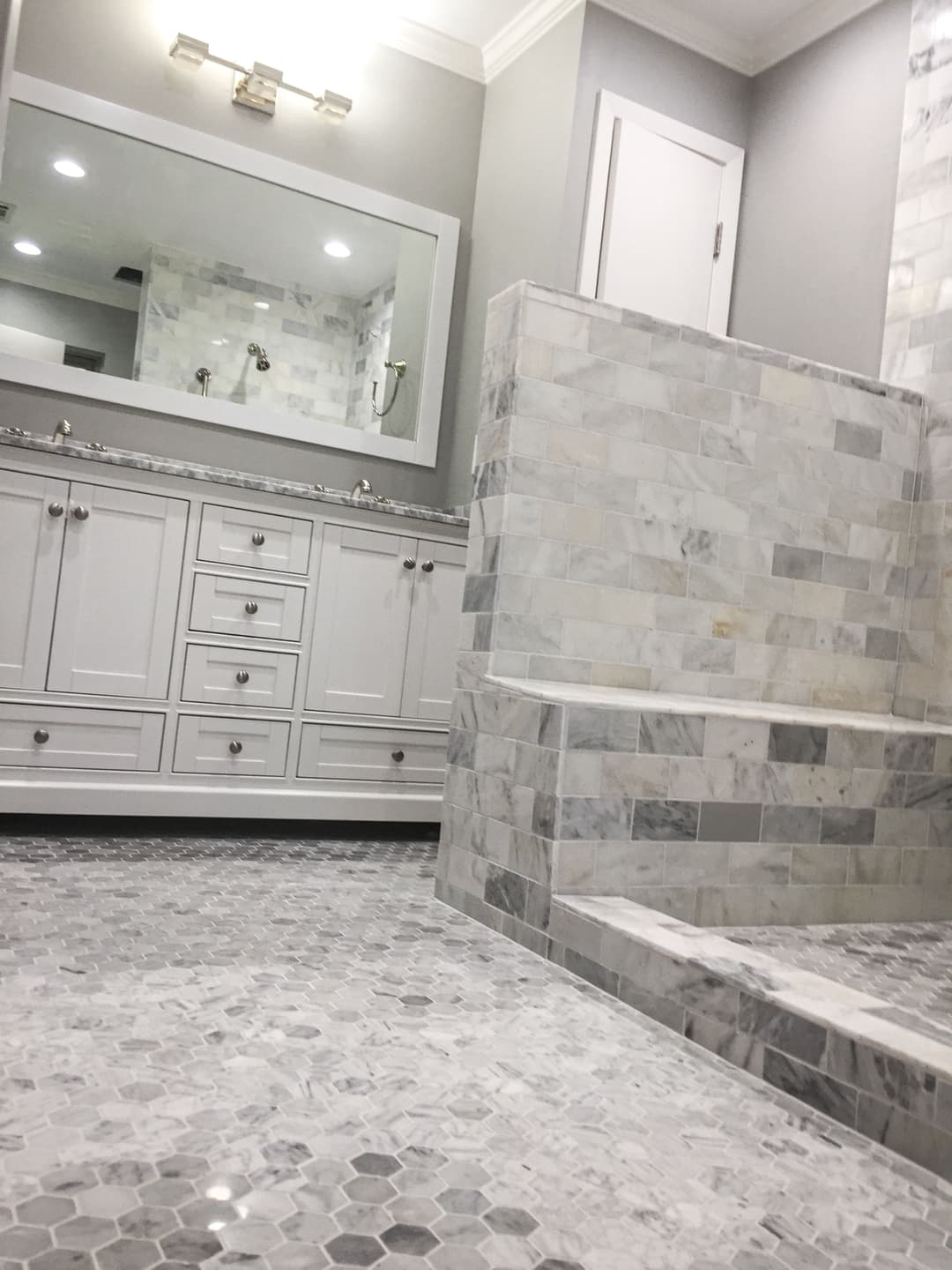 Modern bathroom featuring marble tile floor, sleek cabinetry, and spacious shower area.