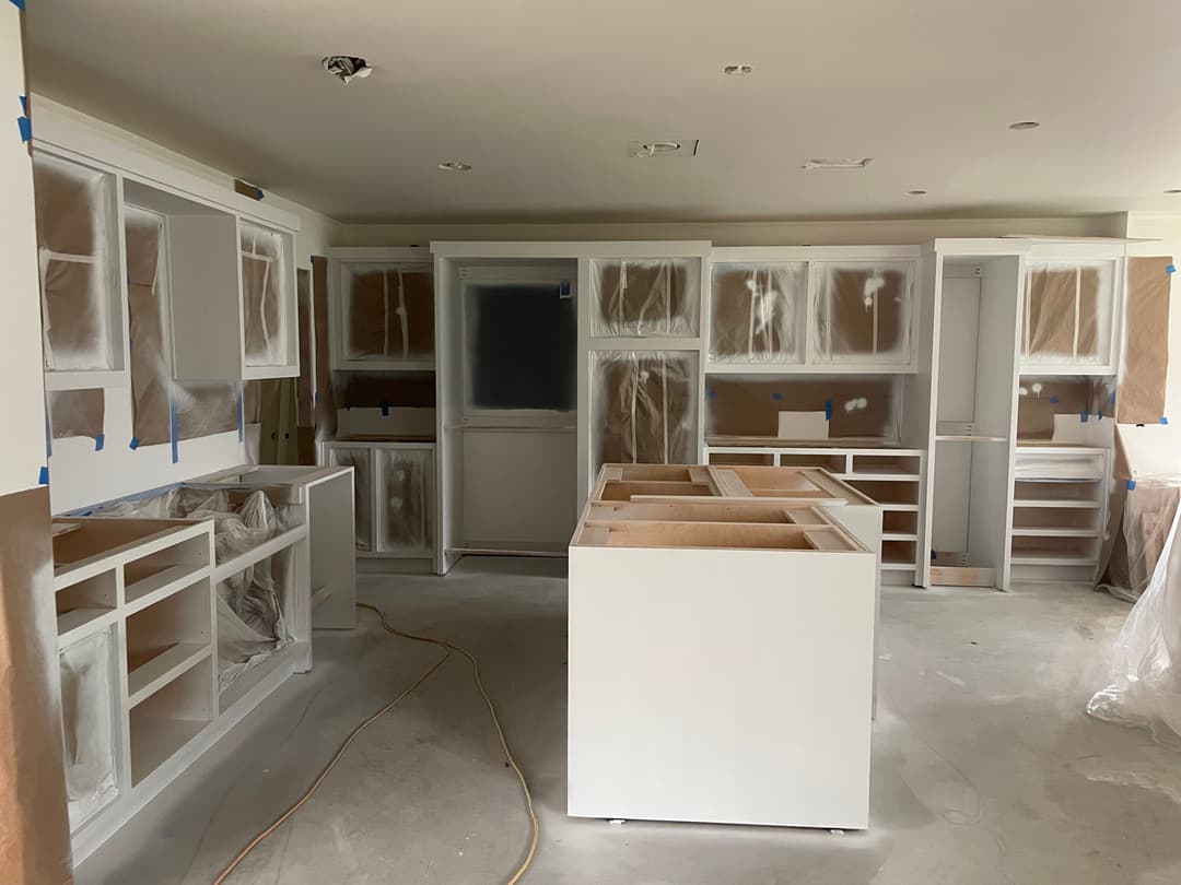 Newly renovated kitchen with white cabinets and unfinished countertops, under construction.