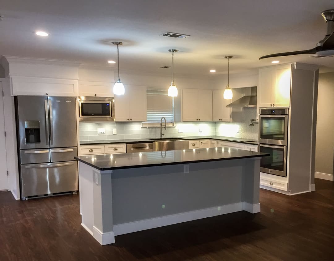 Modern kitchen with stainless steel appliances, pendant lights, and sleek countertops.